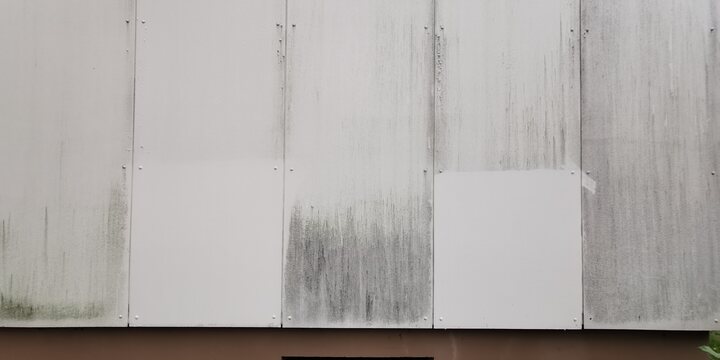 Musterflächen auf Eternit-Faserzementplatten — zwei gereinigte Testfelder auf verschmutzter Fassade