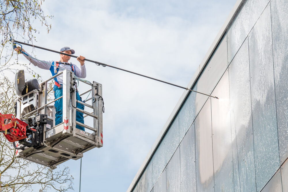 Hebebühne bei der Fassadenreinigung vor blauem Himmel