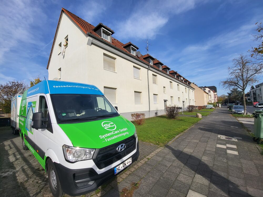 SC-SystemCare-Einsatzfahrzeug, gebrandet, vor einem Objekt